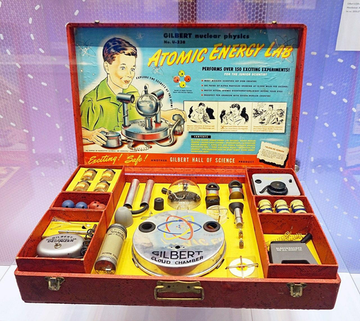 An open wooden toy box with components marked "Atomic Energy Lab"