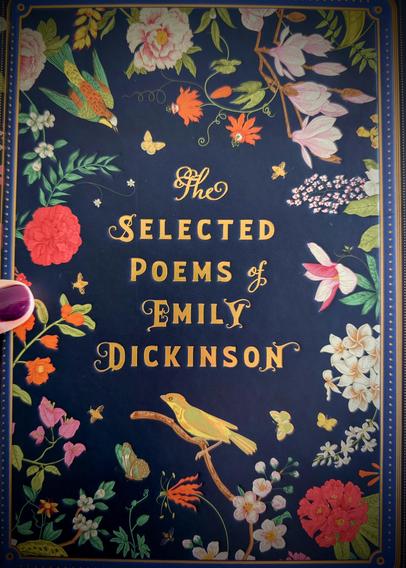 Ein dunkelblaues Buch mit bunten Blumen, Vögeln & Schmetterlingen drauf.

In gelb goldenen Lettern steht der Titel
"The selected poems of Emily Dickinson" mittig drauf.