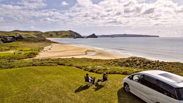 Campervan parked - right-hand corner. Space Travellers sitting on camping chairs to enjoy the view. Photo taken slightly from above.