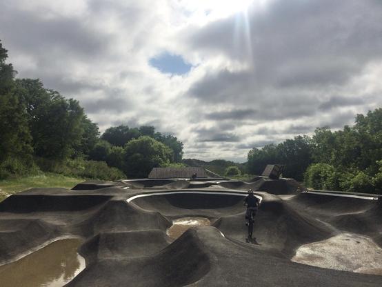 Two guys riding bikes on a pump track.