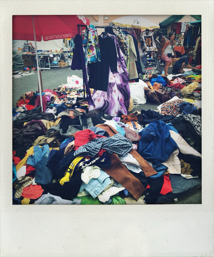 Foto zeigt einen Marktstand mit Second Hand Kleidung in Lissabon. Kleidung liegt chaotisch durcheinander. 