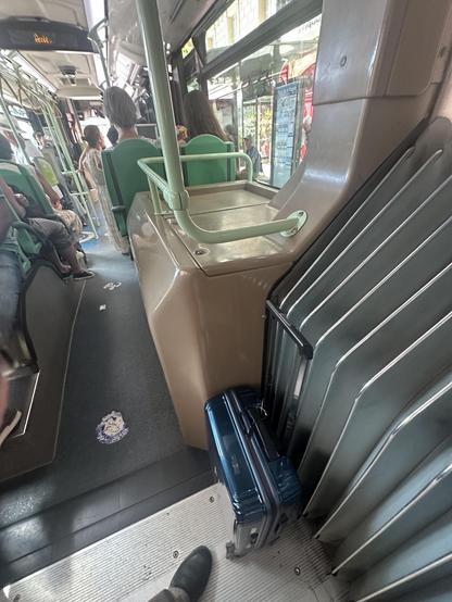 Foto aus dem Bus. Zu meinen Füssen mein Rollkoffer. Ich blicke nach vorne. Man sieht ein paar Fahrgäste.