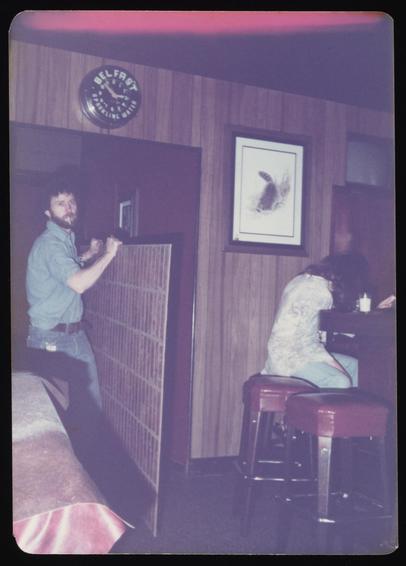 Bartender John Swindle moving interior wall panel for window installation