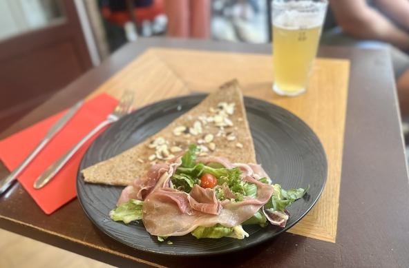 Eine Galette (dreieckig zusammengefalteter Buchweizen-Pfannkuchen) mit etwas Salat und Rohschinken.