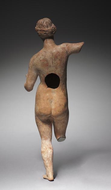 Terracotta figurine of Aphrodite. She is missing her right leg from the knee down and her right arm from the middle of the upper arm. She has a hole in her back but a beautifully crafted bottom and detailed braided hair.
