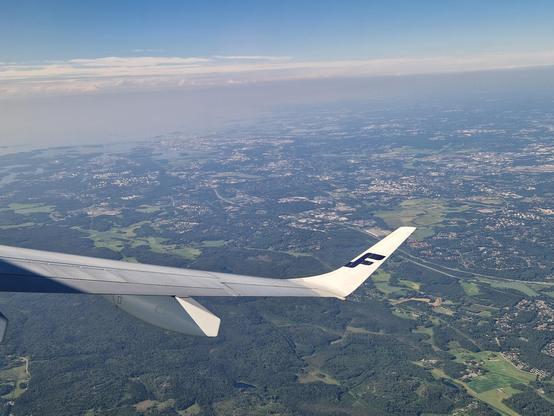 Helsinki, the sea in the distance, seen from an aeroplane window, the Finnair "F" seen on the tip of the wing. 