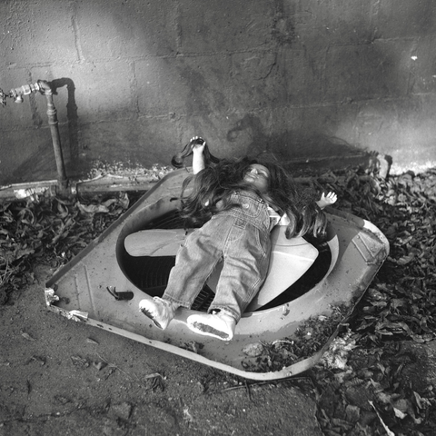 A black and white film photo. A discarded child’s doll rests on top of a large fan blade outside an abandoned building in East Austin, Texas. Wednesday, November 6, 2024.