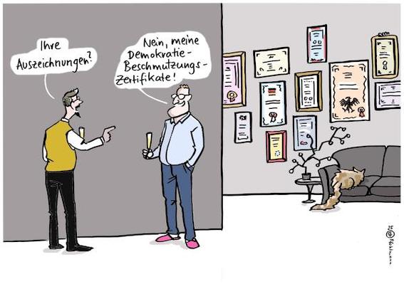 Jens Spahn hat Besuch von einem Herrn, der interessiert auf die vielen Urkunden oder Dokumente zeigt, die hinten an der Wand von Spahns Wohnung hängen. Er fragt: "Ihre Auszeichnungen?" Spahn antwortet: "Nein, meine Demokratie-Beschmutzungs-Zertifikate!"