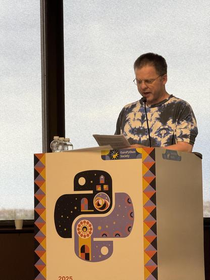 Nicholas Tollervey giving a eulogy in a psychedelic batik shirt.