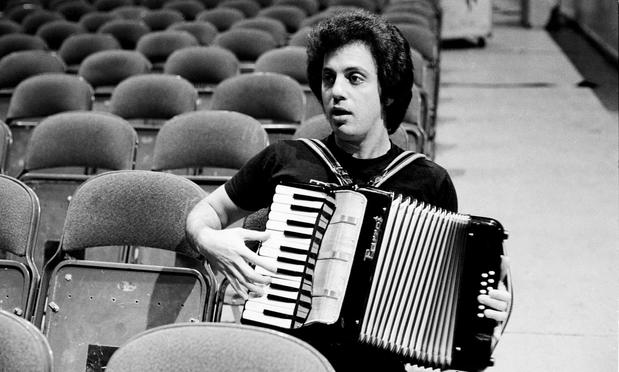 Billy Joel playing a little 12 bass Parrot piano accordion in the seats of an empty auditorium.