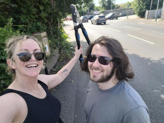 Me holding up shears like She-Ra with my husband smiling next to me, our conquest languishing behind us