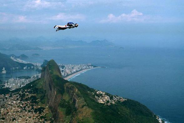 Felix Baumgartner in a wingsuit flying over a mountain. 