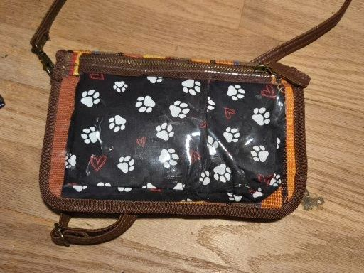 A small back with a cloth decoration inside it. The decoration has a pattern of paw prints and hearts.