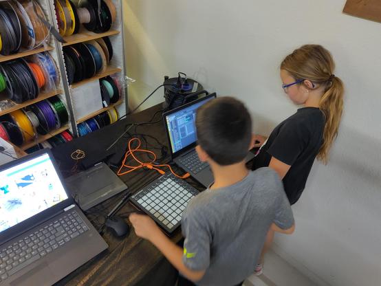 Two kids making music using a groovebox and a laptop with lmms.