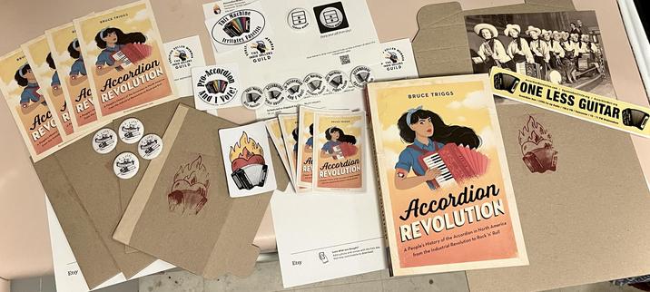 Copy of my Accordion Revolution book with many stickers and buttons from my Etsy shop, spread out before packing to mail. 