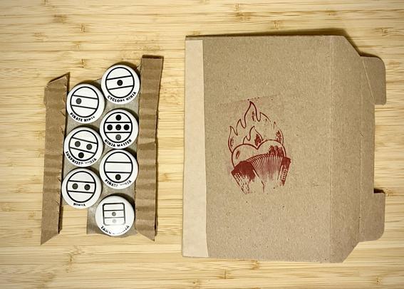A set of seven round white button badges with accordion register symbols of lines and dots that look a bit like cartoon stick figure ninja faces. 