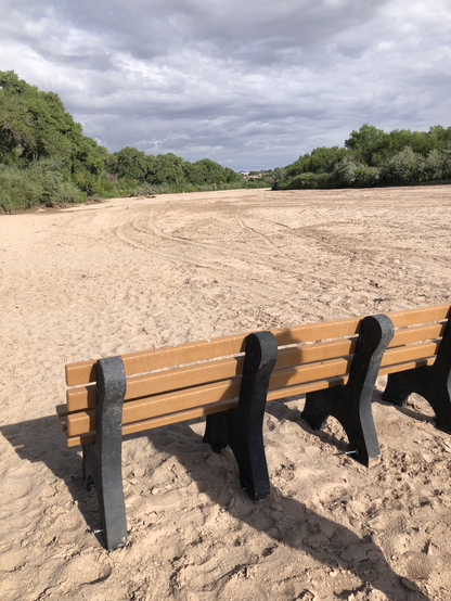 Someone dragged a park bench on the dry sandy riverbed. ATV tracks visible in the sand.