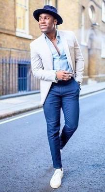 A Man happy standing on a street mostly wearing blues of different hues