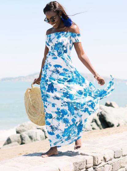 A beautiful woman in a gorgeous long blue and white sundress walking by the beach on the Sea shore 