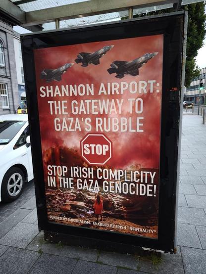 Poster Text:  

SHANNON AIRPORT:
 THE GATEWAY TO
  GAZA’S RUBBLE

STOP 🛑 

STOP IRISH COMPLICITY 
IN THE GAZA GENOCIDE 

Funded by Imperialism 
Enabled by Irish “Neutrality” 

Image:
War planes in red sky flying over 
Buildings bombed into rubble.
A child stands looking at the ruins.