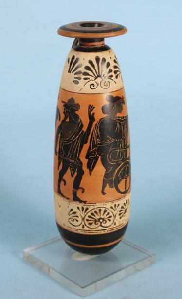 An ancient Greek Attic black-figure alabastron attributed to the Diosphos Painter. The scene depicts Leto stepping into a quadriga, with Apollo holding a kithara. Behind Leto follows Hermes. Above and below are bands of white ground decorated with open and closed palmettes.