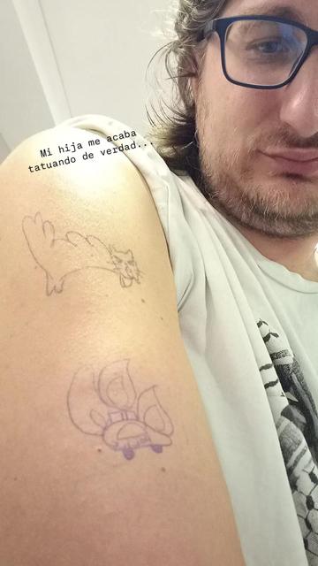 Sale mi brazo con dos dibujos a boli de un gato erizado y un coche de policía en llamas.