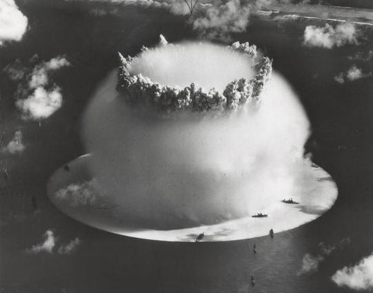 Crossroads Baker, mit dem weißen „Riss“ an der Oberfläche unter den Schiffen und der Spitze der hohlen Gischtsäule, die durch die halbkugelförmige Wilson-Wolke ragt. Im Hintergrund der Strand von Bikini Island.
Quelle: U.S. Army Photographic Signal Corps - http://www.dtra.mil/press_resources/photo_library/CS/CS-1.cfm
Lizenz: Public domain