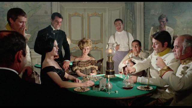 an image from the movie, there are high society people gathered in a parlor room, sitting around a green table with objects on it