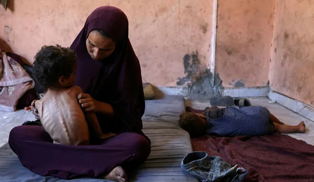 Naeema, a 30-year-old Palestinian mother, sits with her malnourished 2-year-old son Yazan in their damaged home in the Al-Shati refugee camp, west of Gaza City, this week.Credit: Omar El-Qatta/AFP