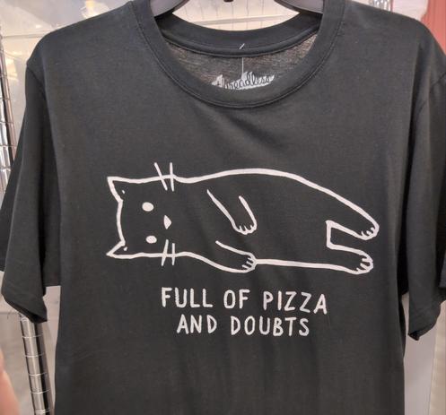 A black T-shirt with a cat laying down a a text underneath the cat: "Full of pizza and doubts."