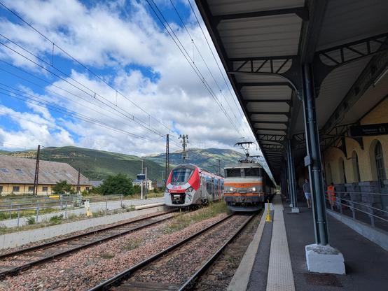 Un TER Regiolis et une locomotive électrique 7200 côte à côte en gare de Latour de Carol Enveitg