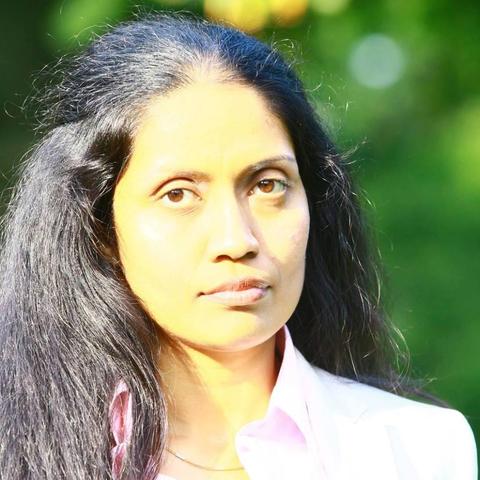 A photo of Anu wearing a light pink shirt.