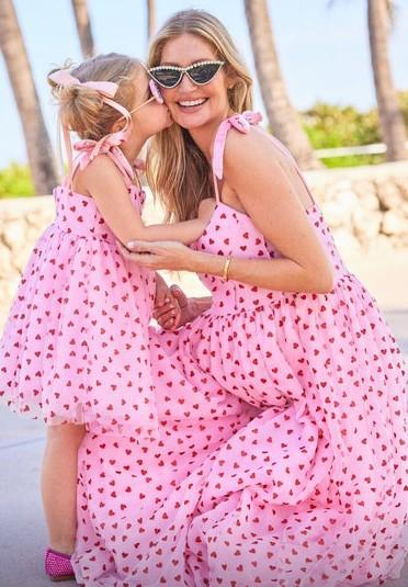 A Mother and her Daughter together with flowing matching beach dresses of pink hearts patterned material at a Beach 
