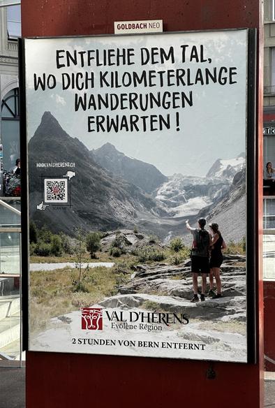 Plakat, zeigt zwei Wanderer, deren einer mit der Hand in Richtung der dahinterliegenden Berge und Gletscher deutet. Sie stehenden einer Ebene, mit einem Flüsschen / Bach.
Der Text darüber sagt: «Entfliehe dem Tal, wo Dich kilometerlange Wanderungen erwarten!».
Das Plakat ist untertitelt:
Val d‘Herens, Evolène Région.
2 Stunden von Bern entfernt.