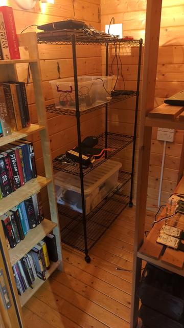 Bookcase no. 9 in the shed and next to it a metal rack with various hardware things and lots of routers not connected.