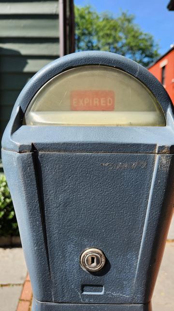 Top of a parking meter with the word expired appearing in white font on a red background