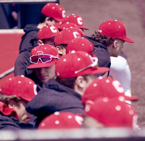 Roughly 12 baseball players in a rough line from front to back with red caps with the letter C and dark hoodies