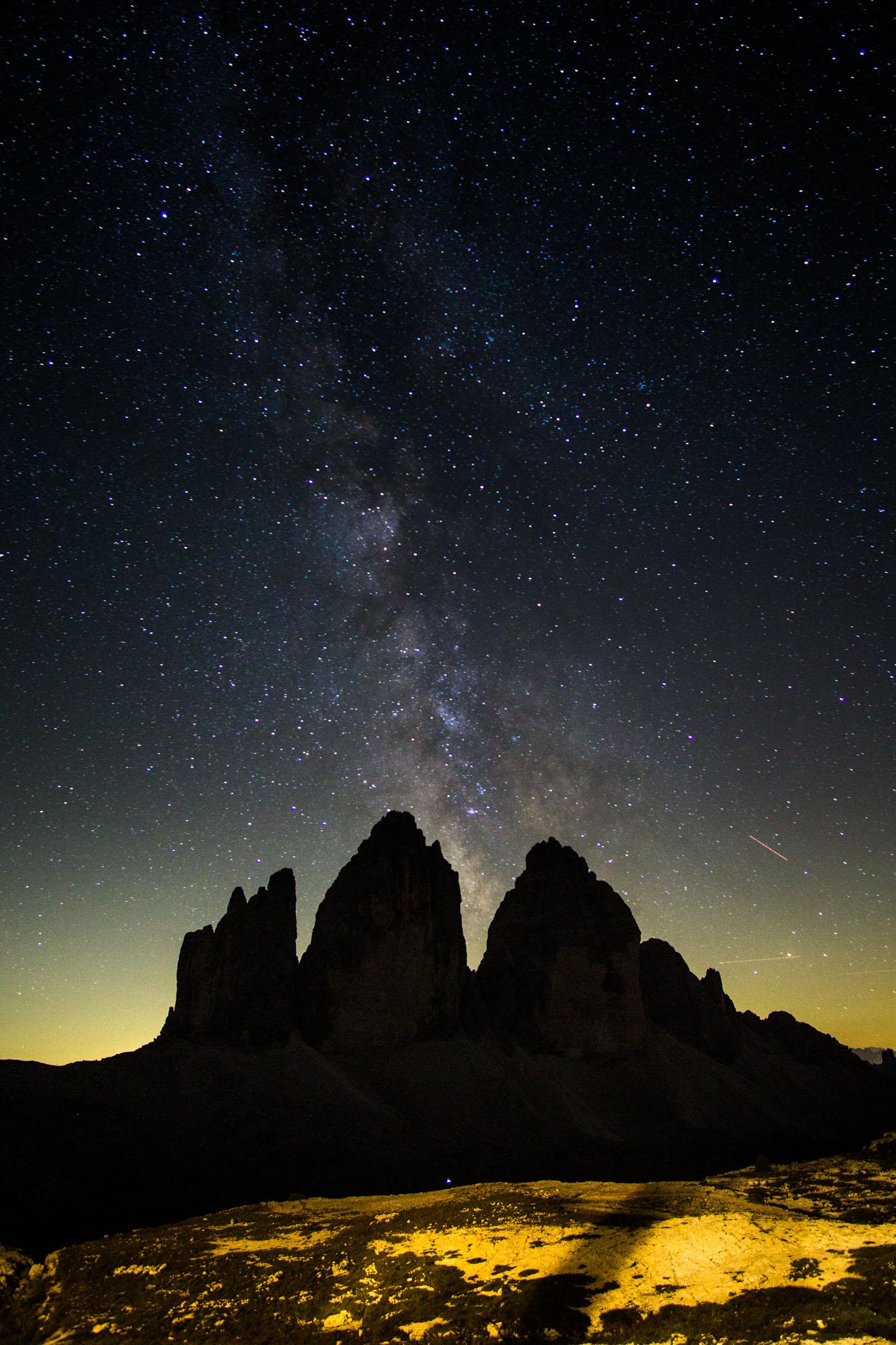 Die Drei Zinnen in den Dolomiten bei Nacht. Hinter den Bergen, die nur als Schattenriss zu sehen sind, steigt die Milchstraße auf. Die Drei Zinnen in den Dolomiten bei Nacht. Hinter den Bergen, die nur als Schattenriss zu sehen sind, steigt die Milchstraße auf.