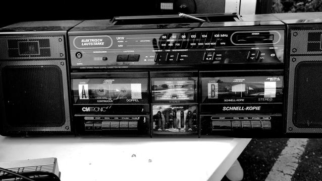 Ein Schwarz-Weiß-Photo. Viel Kontrast. Darauf ist eine alte Boom-Box mit Doppel-Kassettendeck.