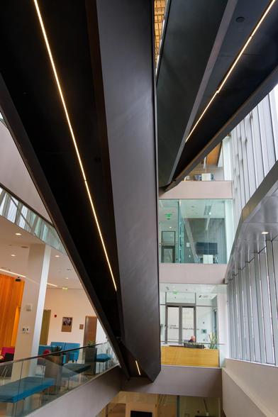 The black undersides of two staircases look prismatic in an otherwise mostly white interior of a building with lots of glass windows