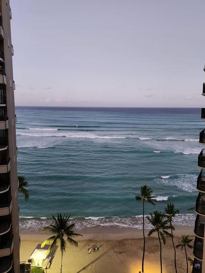 Photo shows a beach and ocean framed between two buildings