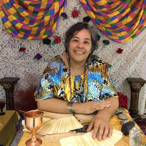 Mulher de pele morena, cabelos ondulados e grisalhos, com expressão serena. 