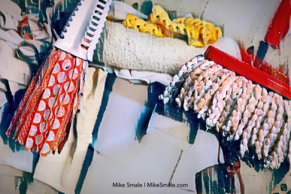 Bright colours and abstract forms combine to create a modern interpretation of cleaning tools, including two mops, brushes, and a roller. Abstract bins covered in blankets are in the background.