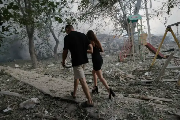 Residents pass by the site of a Russian airstrike that destroyed a residential house in Kramatorsk.  The playground is strewn with rubble.