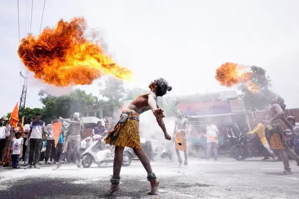Participants perform a fire-breathing stunt as they take part in a religious procession.
