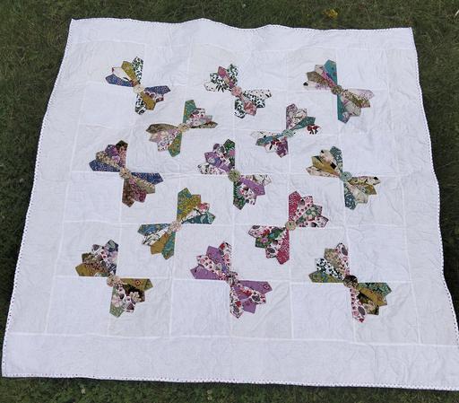 56 x 56 in (142 x 142 cm)  a photo of a quilt, it has about a dozen multi-colored bow tie designs against a white background