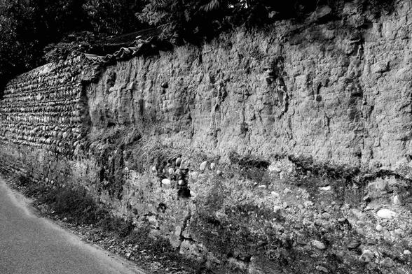 Retrait d'un enduit au ciment sur un mur de pisé