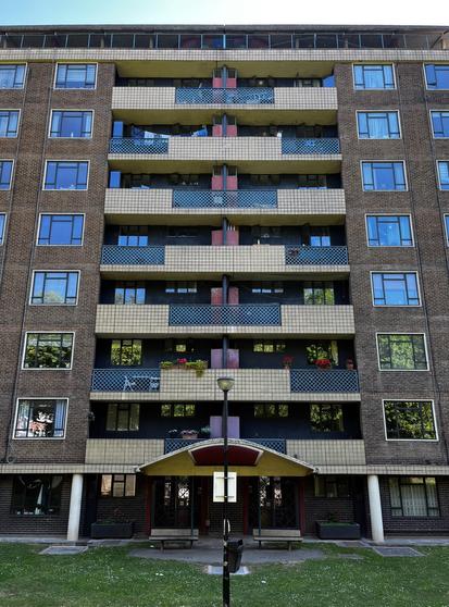 Ground level shot looking up at an 8 storey building, focusing on the balconies. These alternate with tiles at the sides and latticed fencing in the middle, and vice versa. The balconies are inset into the building and either side of them is a grid of clean, PVC windows.