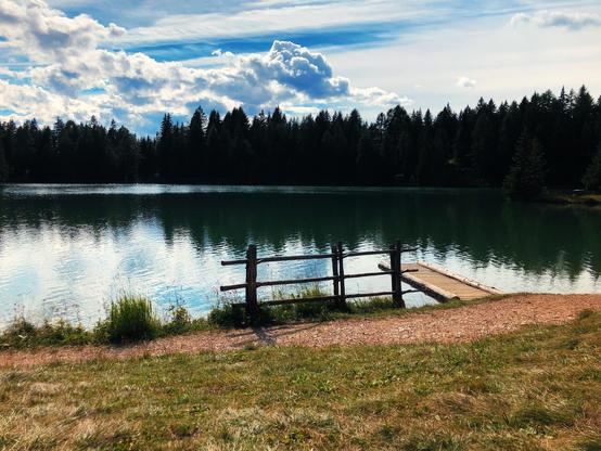 A mountain lake surrounded by trees and clouds in the sky