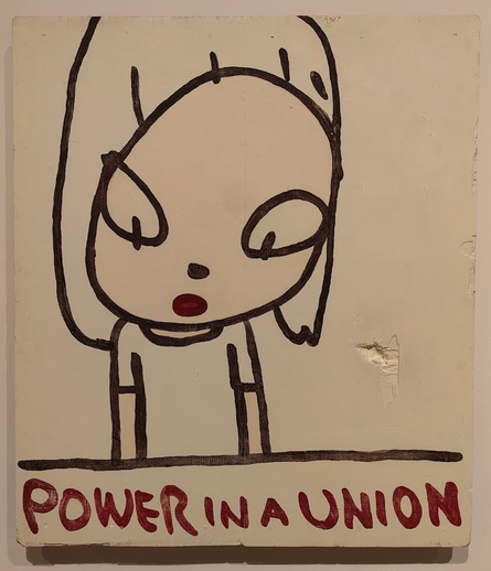 A photograph of an artwork by Yoshitomo Nara. The image is a painted sketch of a child like figure with the words "Power in a Union" underneath